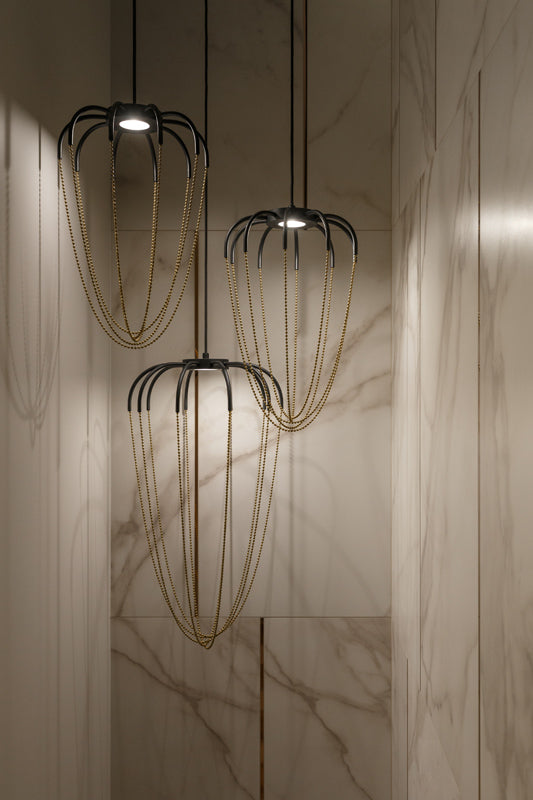 Axo Light Alysoid Pendant with brass beads hanging in a group in a marble tiled staircase