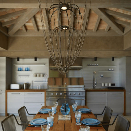 Axo Light Alysoid Pendant with brass beads hanging in a row over a dining table with blue plates