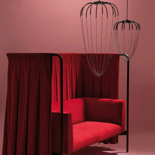 Axo Light Alysoid Pendants with black beads hanging in front of a red chair in a pink room