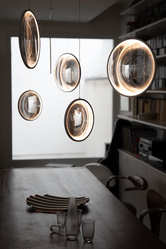 DCW Editions black Focus pendant with 4 circles over wooden dining table with large window in background