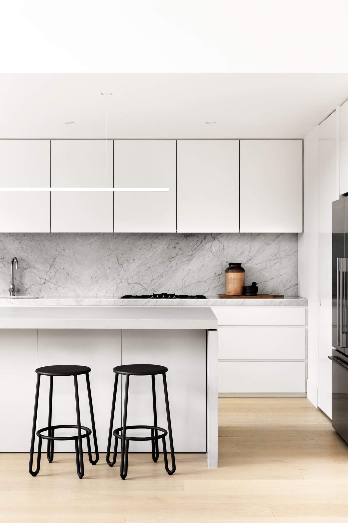 Highline Linear Pendant in White in White Kitchen with Black Stools
