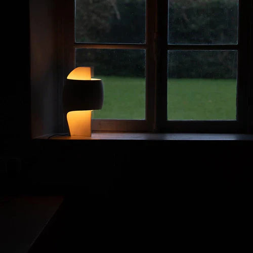 DCW Editions Lamp B table lamp on window sill, warmly lit