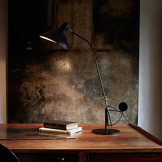DCW Editions Mantis table lamp on wooden desk with 2 books