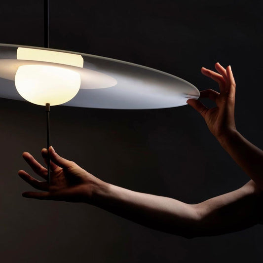 DCW Editions Mono pendant being held by person tilting the shade and dimming by the stem