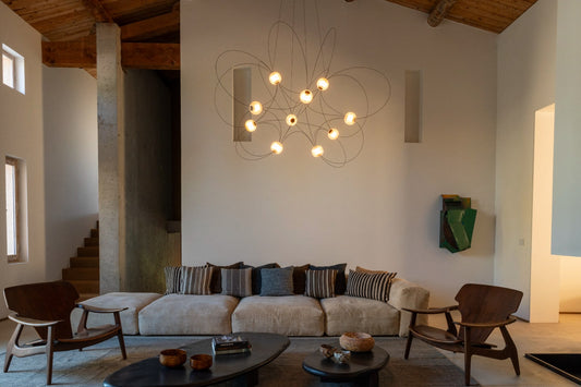 DCW Editions Munari pendant with 10 illuminated acrylic spheres and curved rods in lounge low furniture and wooden ceiling