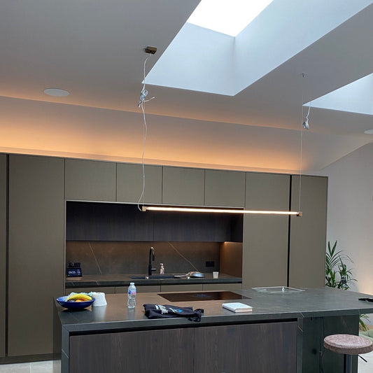 Modern kitchen with LED lighting, linear pendant over kitchen island, grey cabinets and a skylight