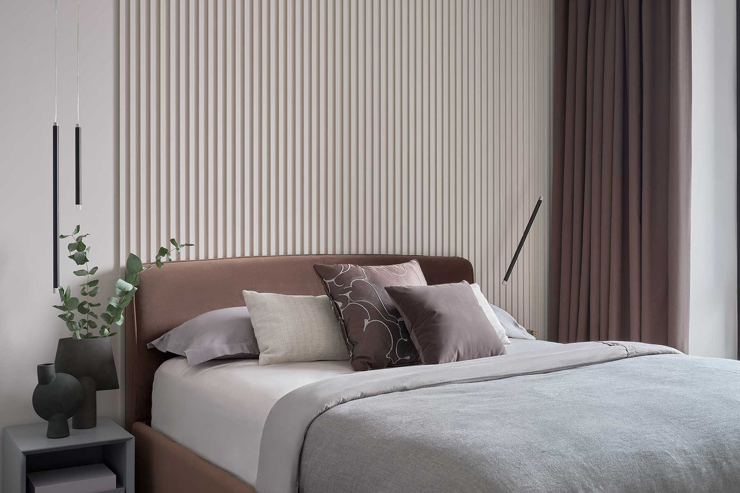 Lodes A-Tube Nano Duo and Nano pendants hanging on each side of a bed with grey bedding