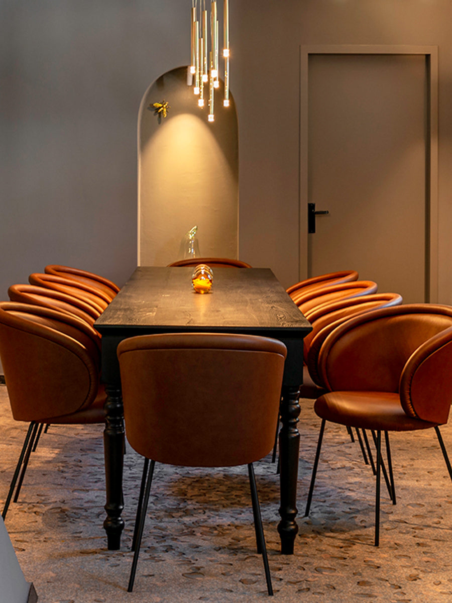 Lodes A-Tube Nano pendant over long rectangular table with orange chairs