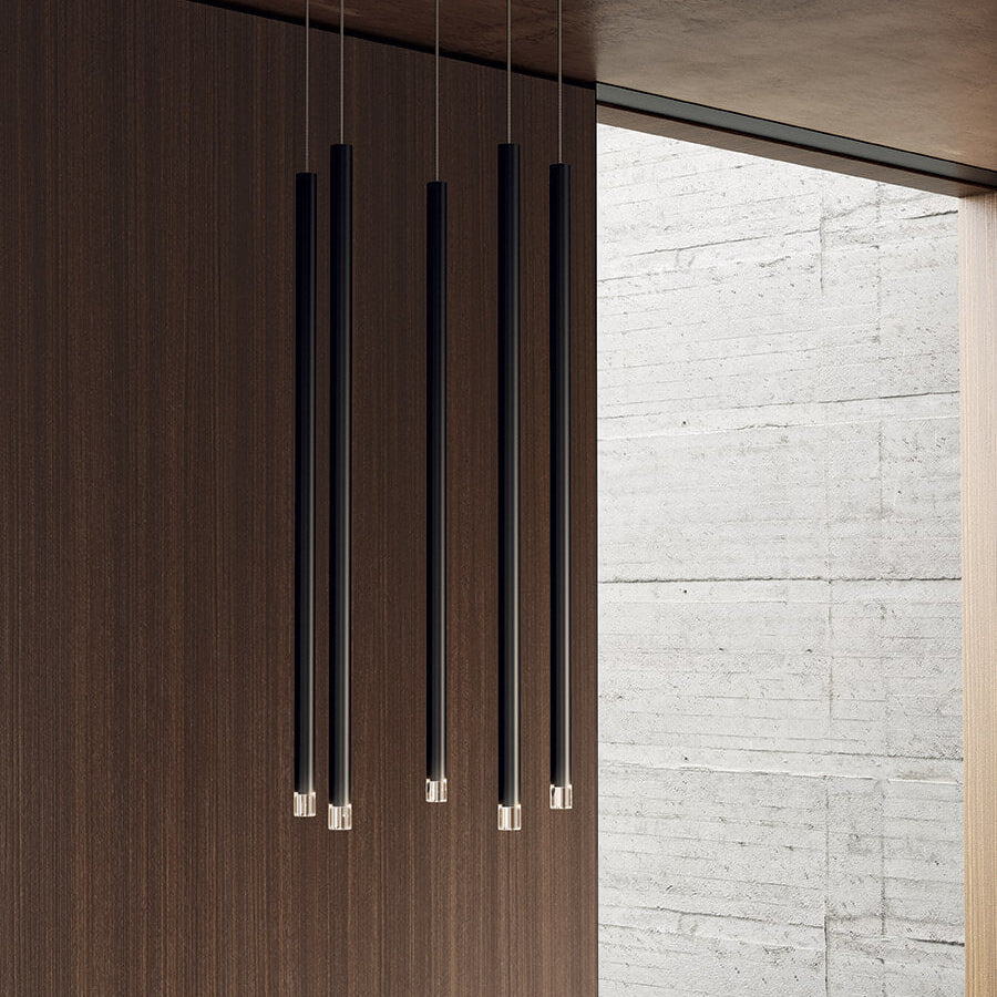 Lodes A-Tube Nano pendant in black against wooden wall with window