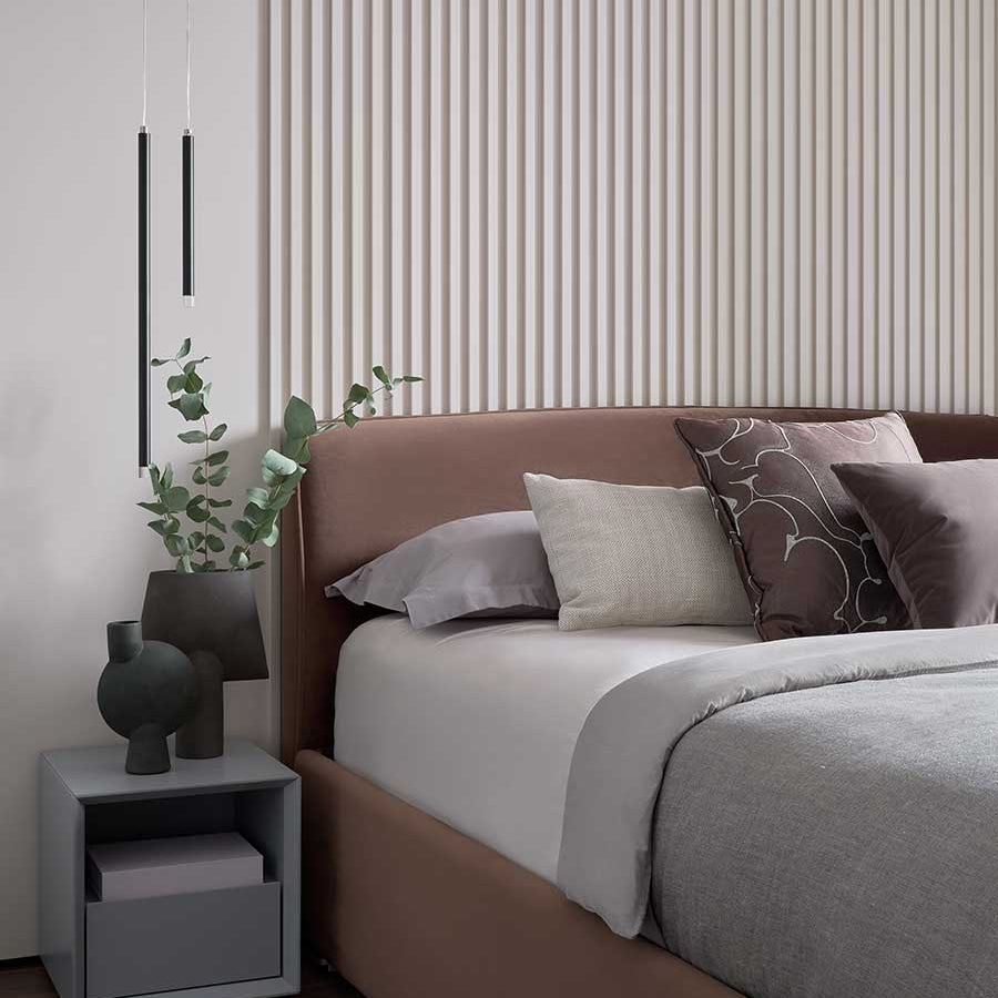 Lodes A-Tube Nano pendant in black by bed with cushions