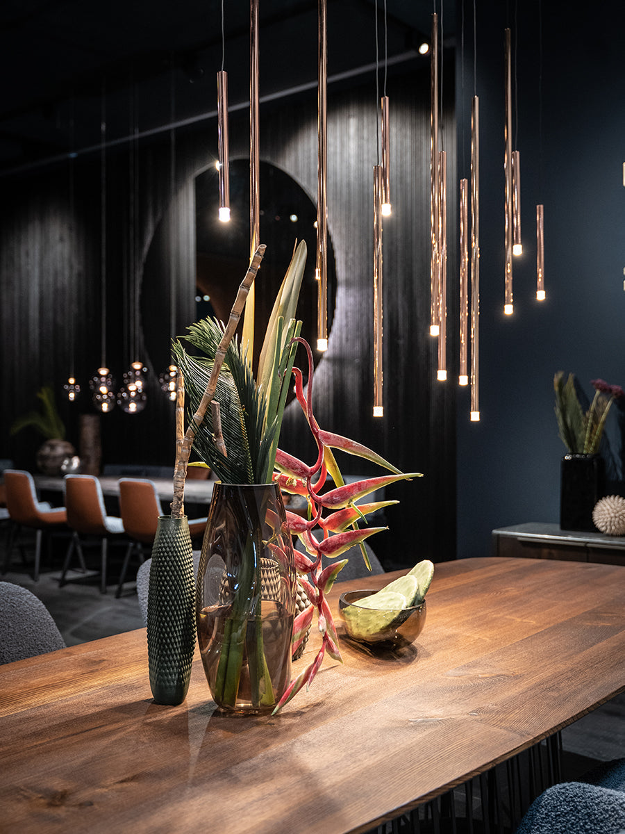 Lodes A-tube Nano pendant in rose gold over dining table with exotic flowers