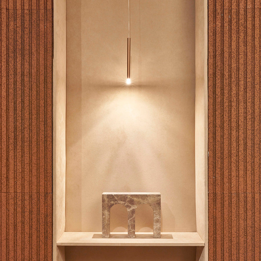 Lodes A-Tube Nano pendant terra finish in niche illuminating a marble sculpture
