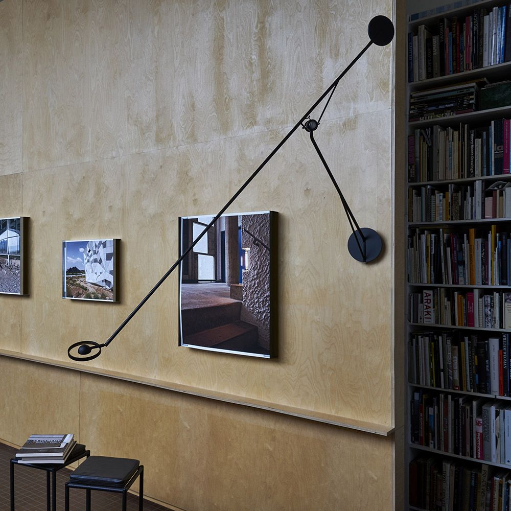 DWC Editions Aaro wall light on yellow wall with art with bookcase