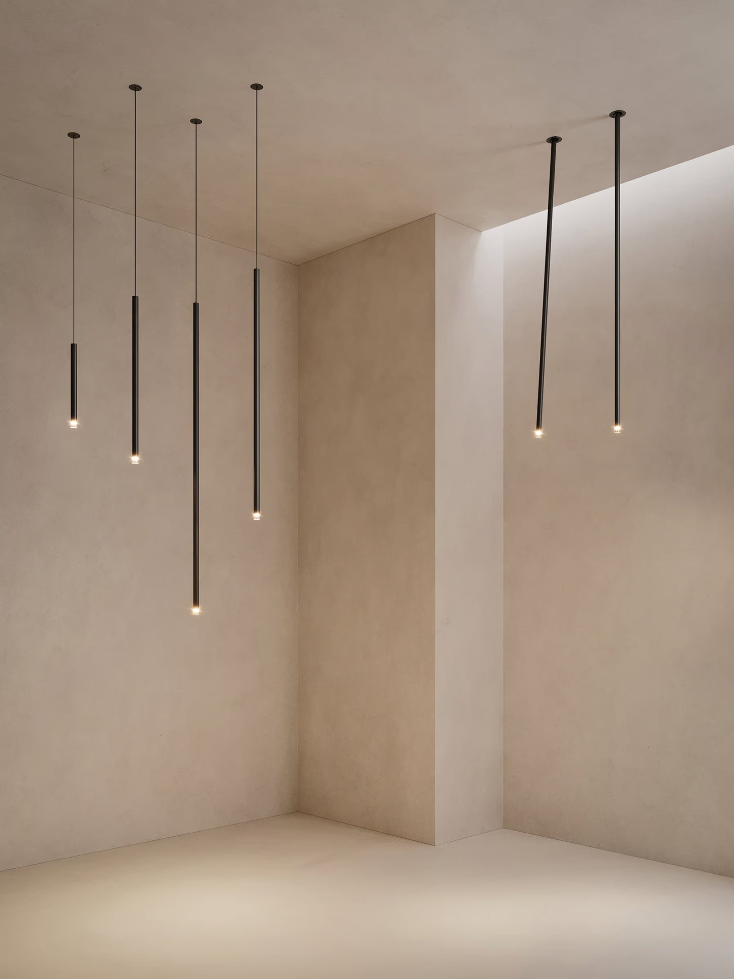 Lodes A-Tube Nano pendants and swing ceiling lights in black finish illuminated in minimalist plaster room
