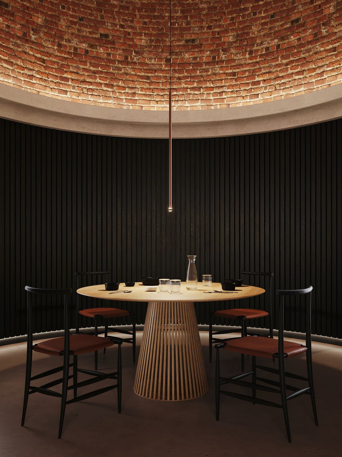 Lodes A-Tube Nano XL pendant n terra finish illuminated over round table with black chairs and brick ceiling with upwards LED cove lighting