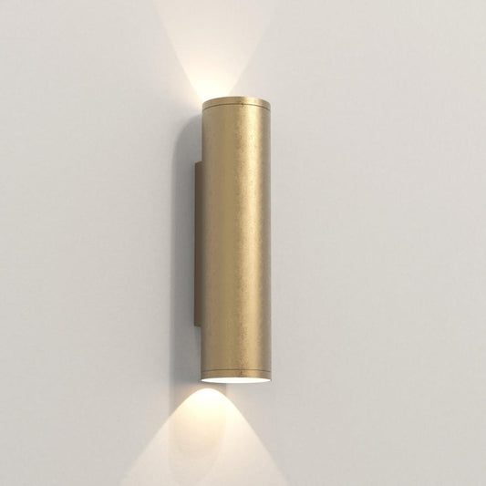 Brass cylindrical wall light fixture on a white wall
