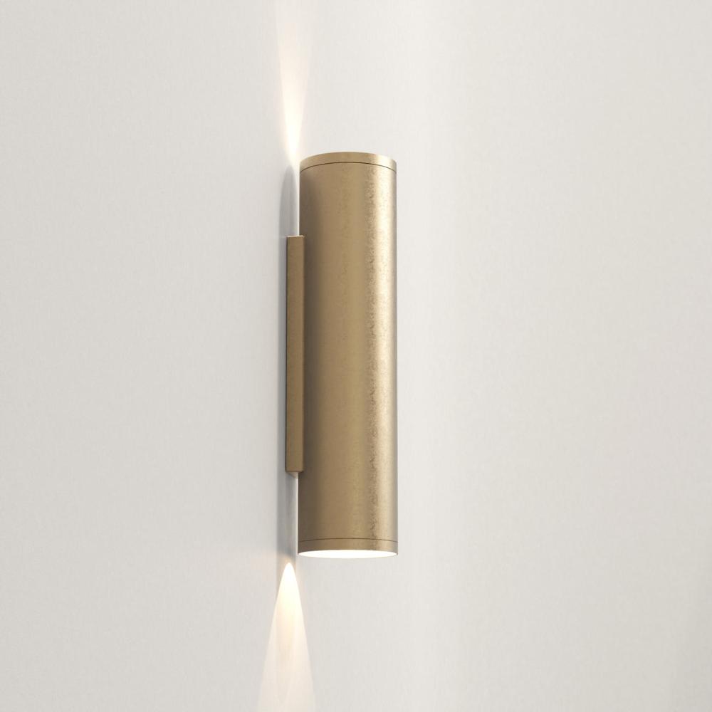 Brass cylindrical wall light fixture on a white background