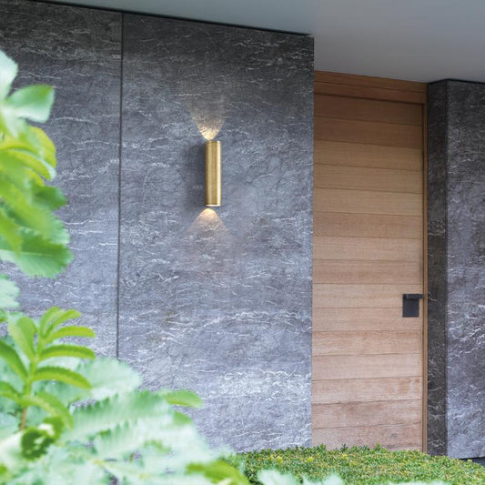 Modern outdoor wall light fixture on a gray stone wall with a wooden door.