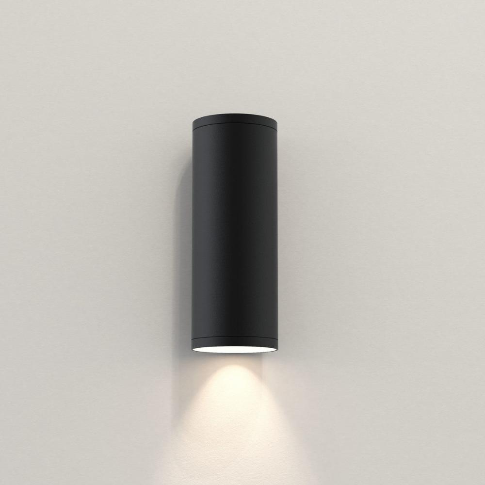 Black cylindrical wall light fixture on a plain background