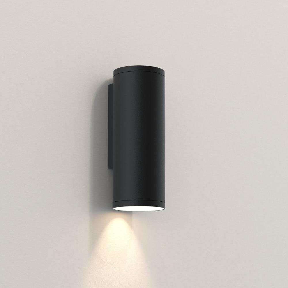 Black cylindrical wall light fixture on a beige wall