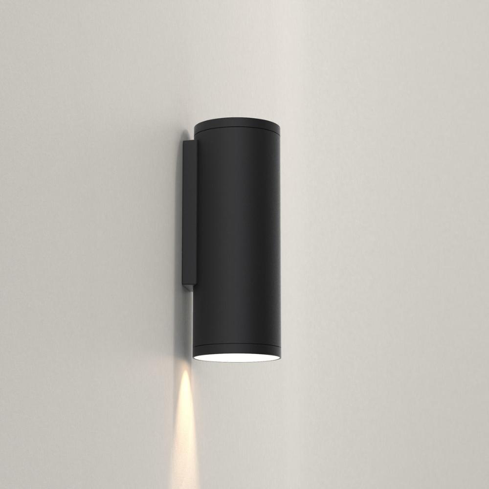 Black cylindrical wall light fixture on a gray wall