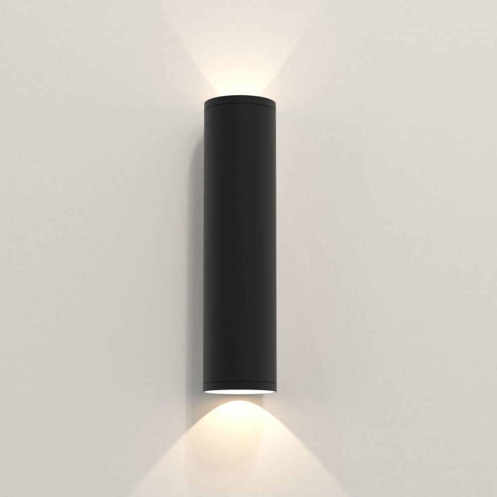 Black cylindrical wall light fixture on a white wall