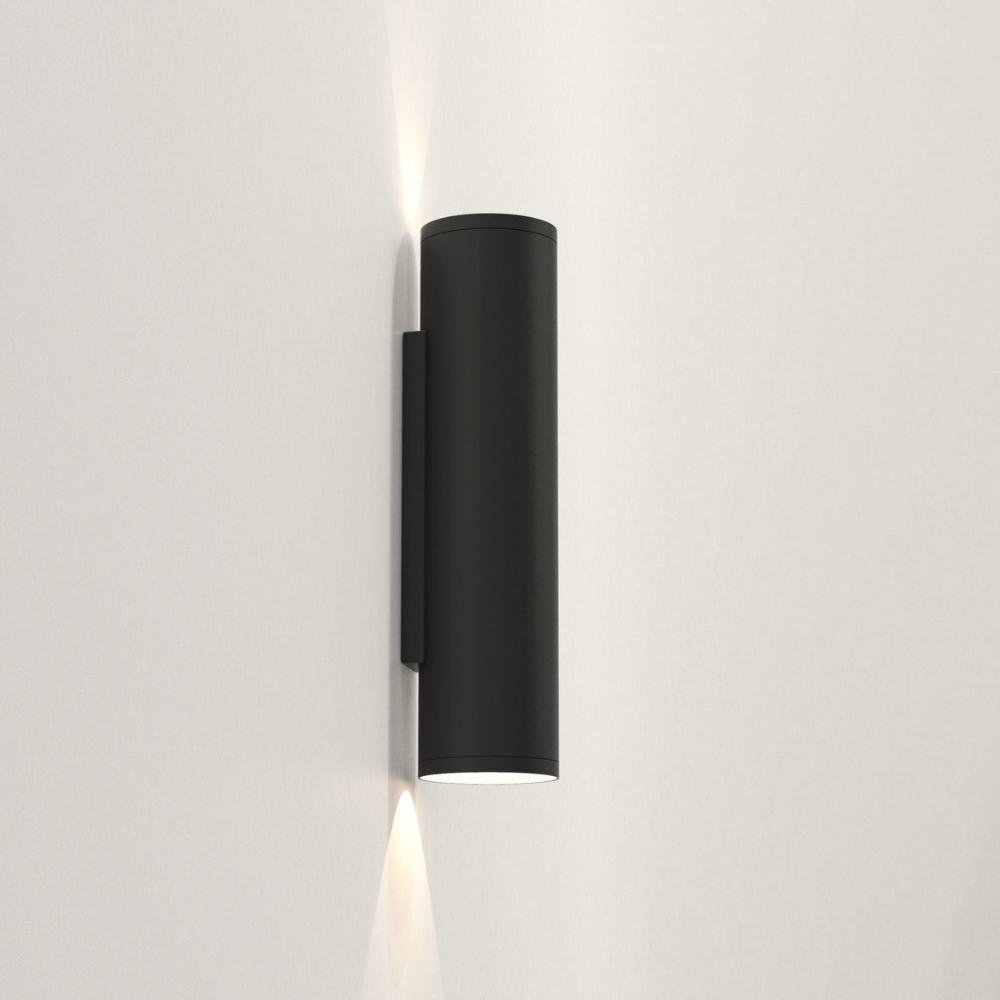 Black cylindrical wall light fixture on a white wall