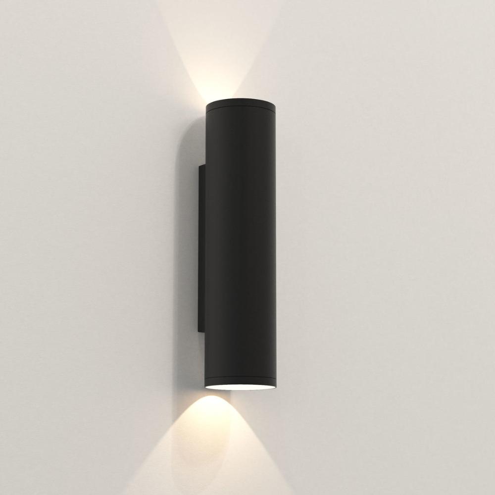 Black cylindrical wall light fixture on a white wall