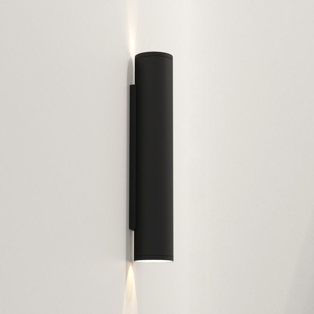 Black cylindrical wall light fixture on a white background