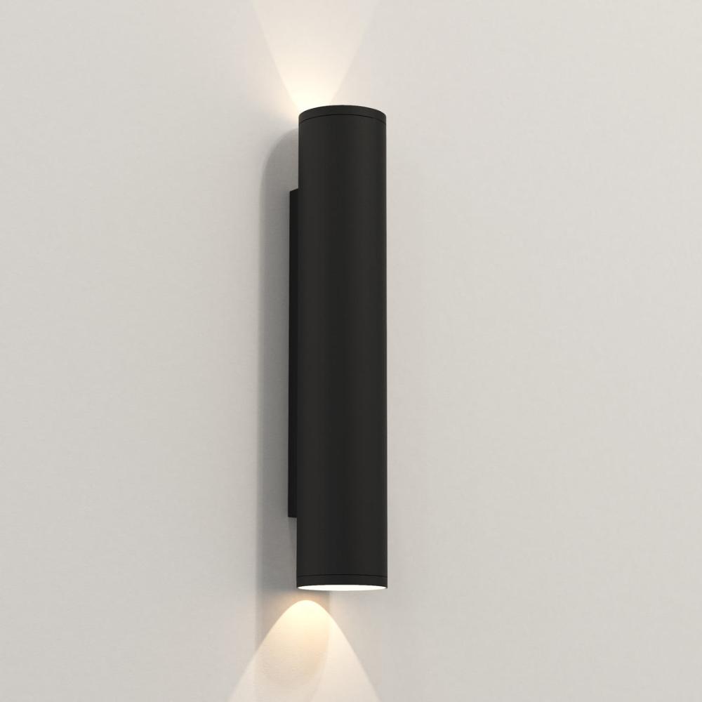 Black cylindrical wall light fixture on a gray wall