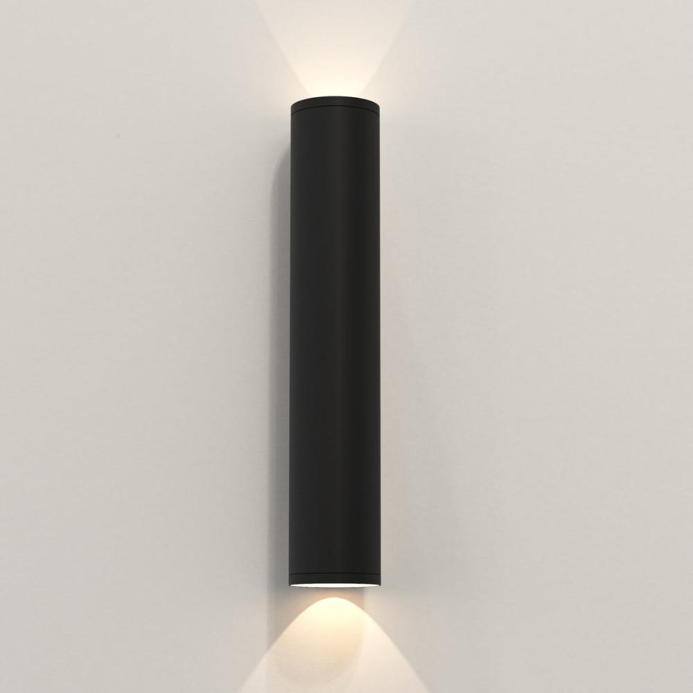 Black cylindrical wall light fixture on a white wall