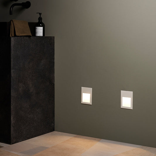 Bathroom corner with dark vanity, bottles, and wall lights on a gray wall.