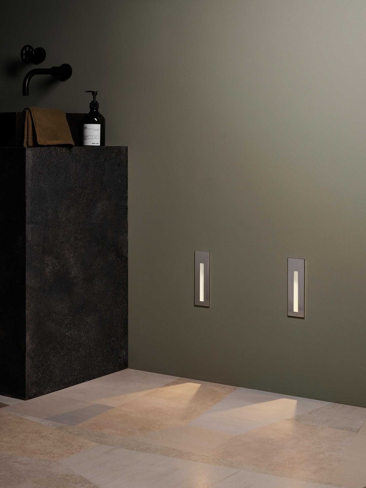 Bathroom setting with a dark pedestal sink and decorative wall lights.