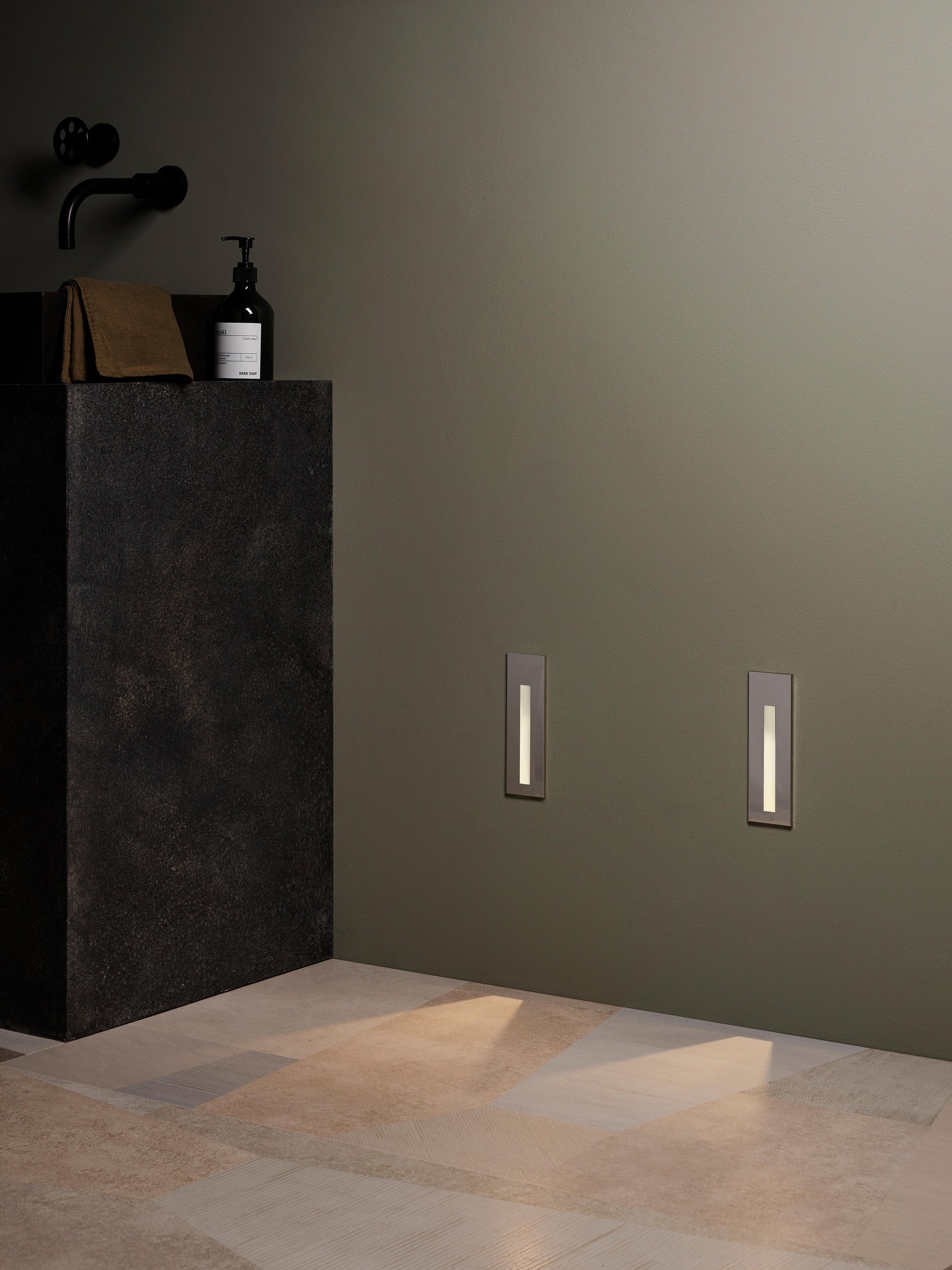 Bathroom setting with a dark pedestal sink and decorative wall lights.