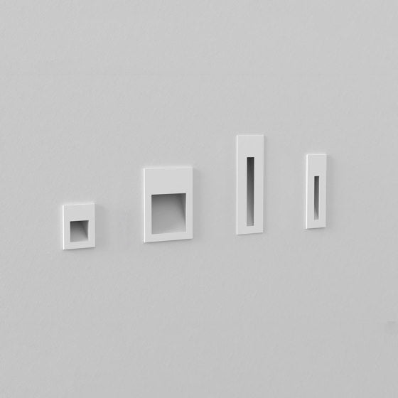 Four white wall-mounted shelves of different sizes on a gray wall.