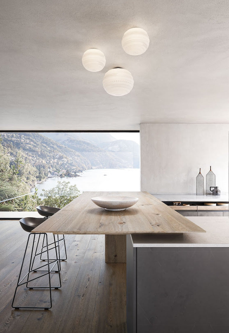 Modern kitchen with wooden dining table and stools, overlooking a scenic view.