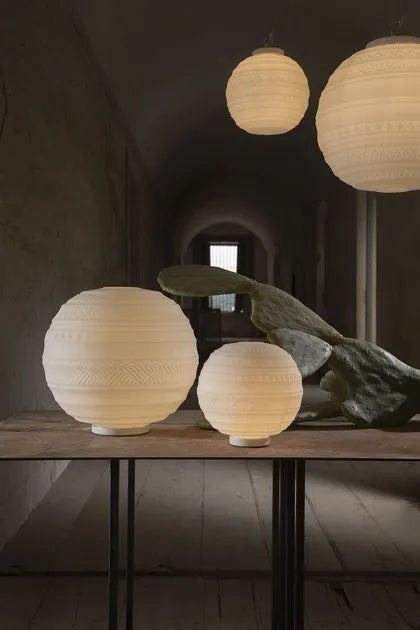 Three spherical paper lamps on a wooden table with a dark background