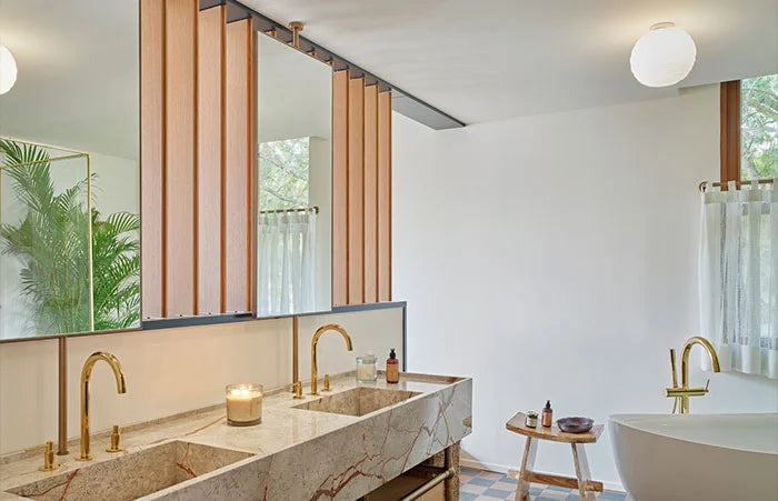 White globe ceiling light over tub with gold taps.