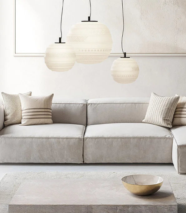 Modern living room with a light gray sectional sofa, decorative pillows, and pendant lights.