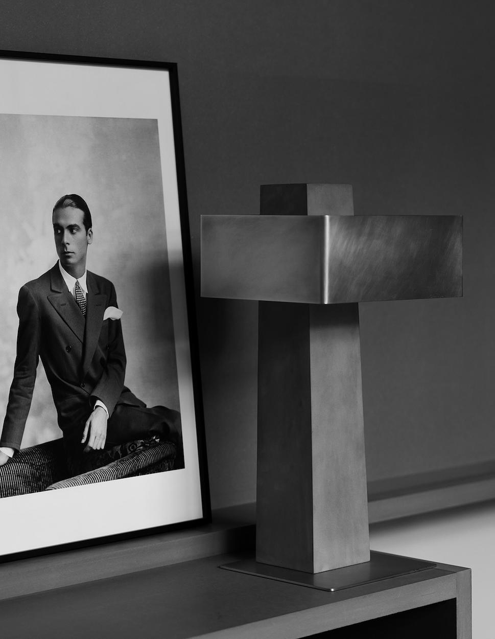 DCW Editions Iota table lamp in brass and bronze next to photo of man in a suit