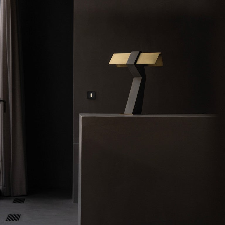 DCW Editions Iota table lamp in brass and bronze in dark room with curtains