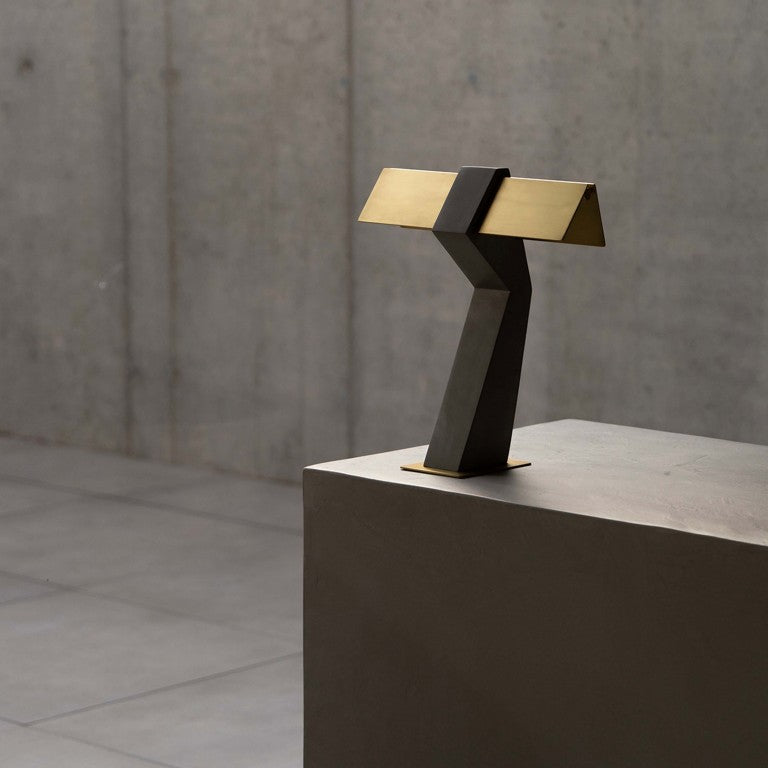 DCW Editions Iota table lamp in brass and bronze unlit on metal table in concrete room