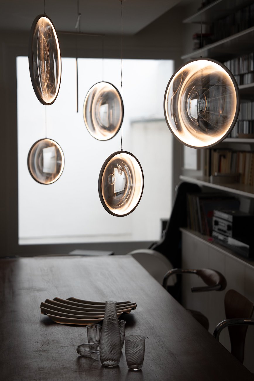 DCW Editions black Focus pendant with 4 circles over wooden dining table with large window in background