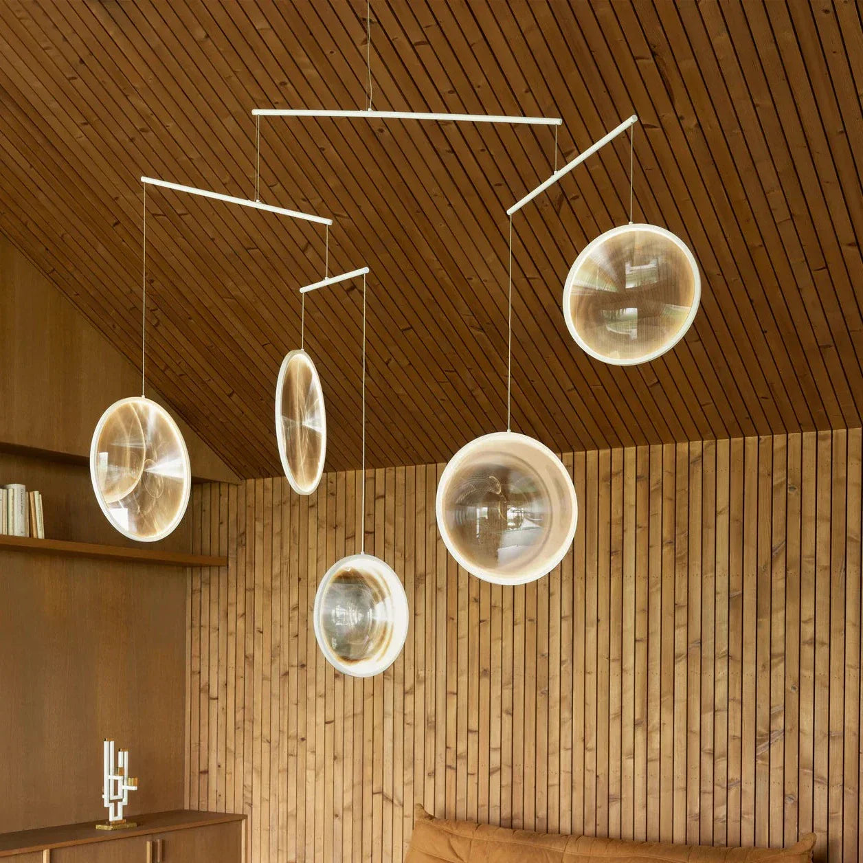 DCW Editions white Focus pendant with 5 circles in room with sloped wooden slats