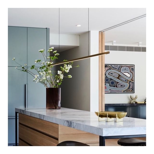 Highline Linear Pendant in Patina Brass over Marble Kitchen Island with Flowers and Art