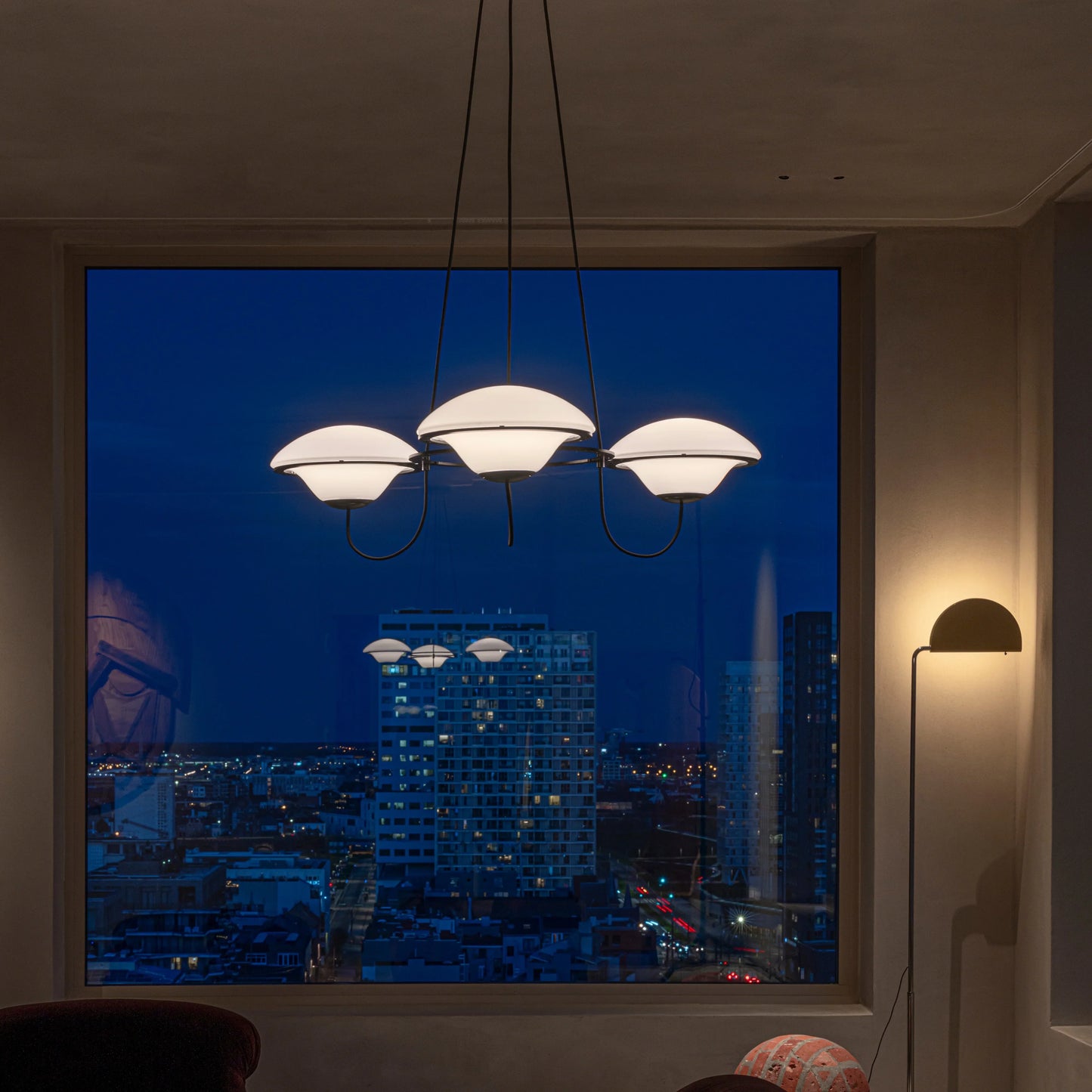 DCW Editions In The Air pendant with 3 shades in modern lounge, lit, in front of window in the evening