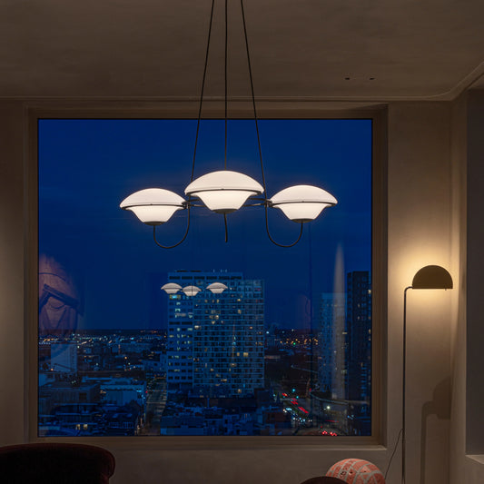 DCW Editions In The Air pendant with 3 shades in modern lounge, lit, in front of window in the evening