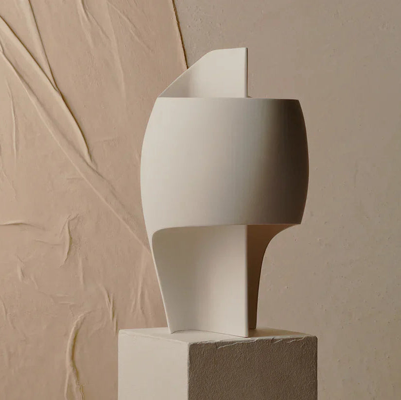 DCW Editions Lamp B table lamp on white pedestal with plastered wall