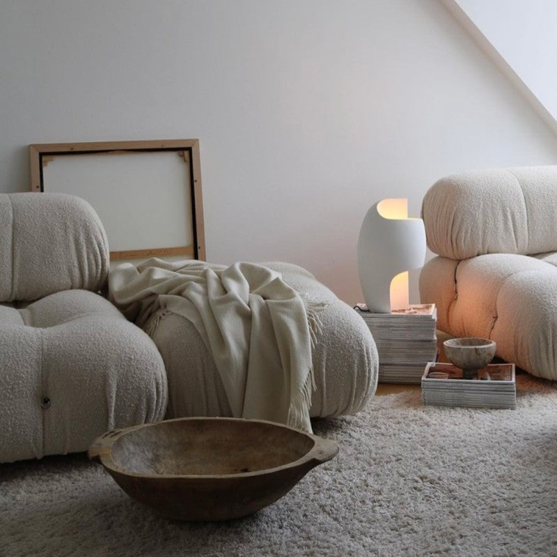 DCW Editions Lamp B table lamp on stacked magazines next to a bubble sofa