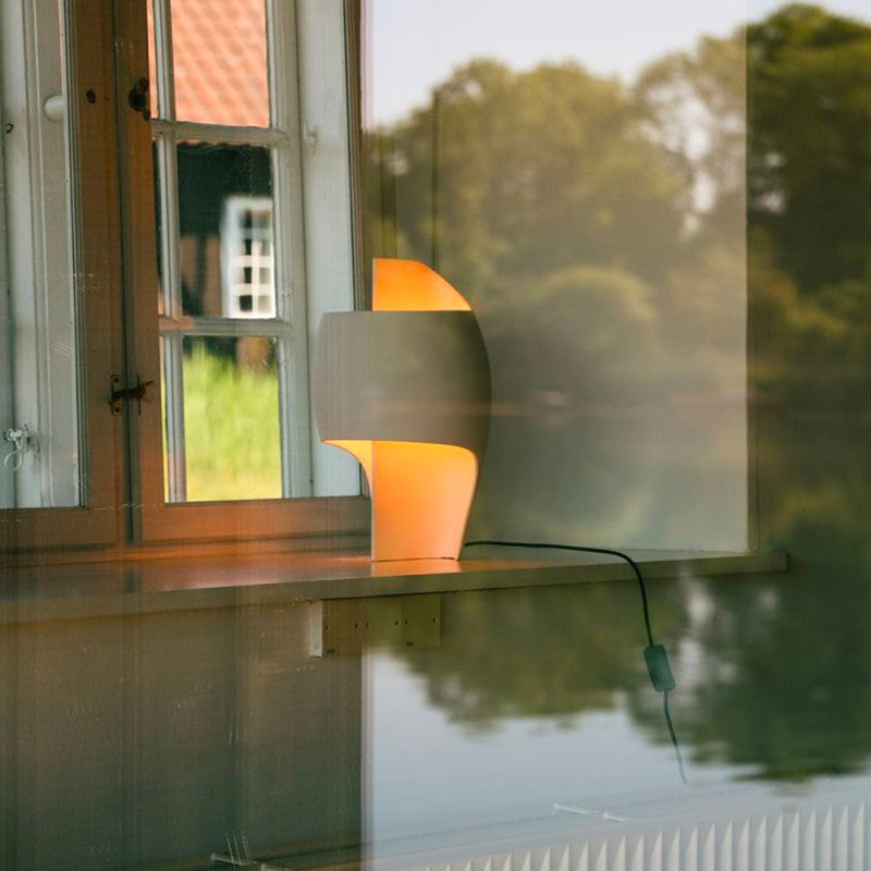 DCW Editions Lamp B table lamp on a window sill through a window with reflections of trees